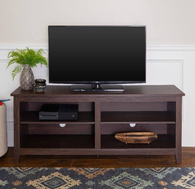 a dark wood entertainment stand with a tv on it