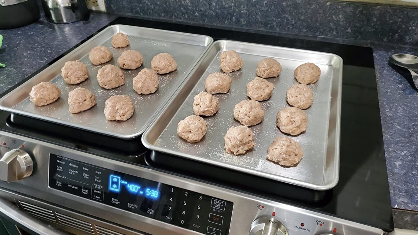 two baking sheets holding about 22 meatballs
