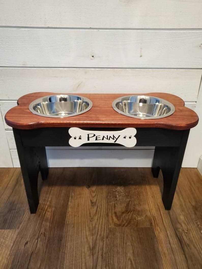 elevated dog feed with a wooden top and a black stand with the name &quot;penny&quot; put on the bone-shaped label