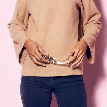 Person holding glass double-ended dildo