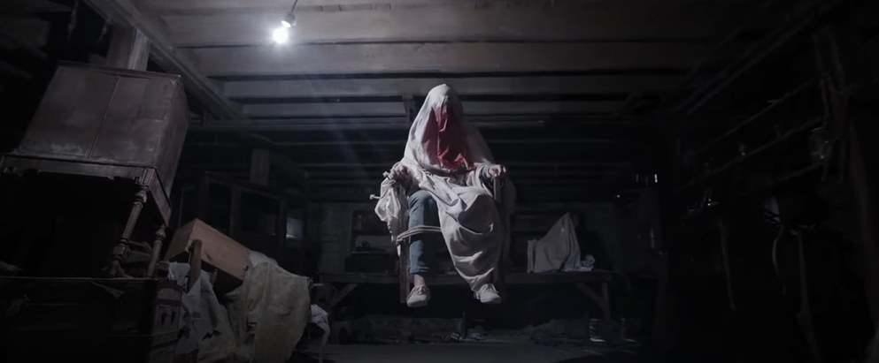 Covered figure tied to a chair, levitating in the basement