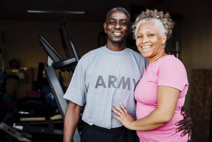 Older husband and wife with their arms around each other. Husband wearing army T-shirt.