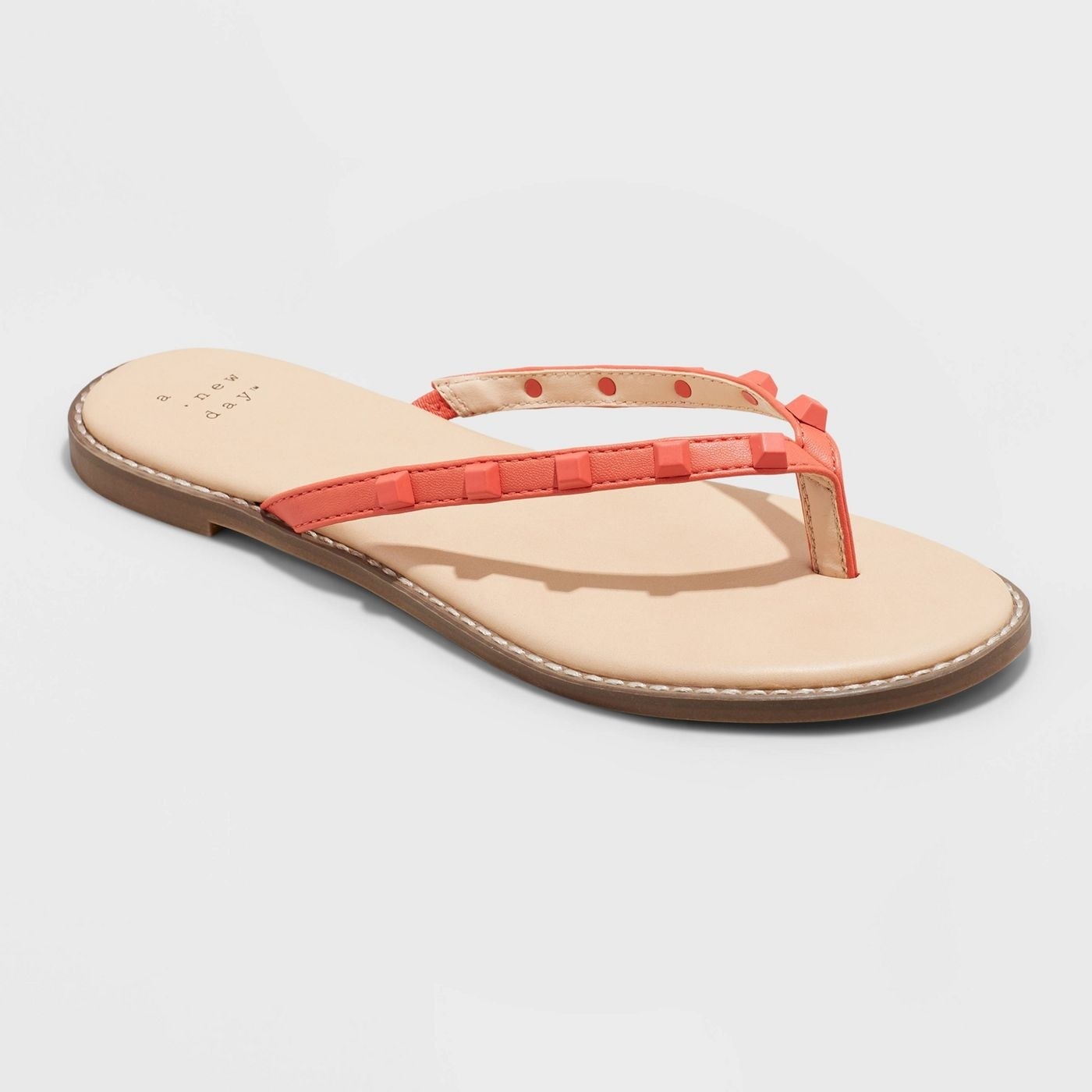 Flip flops with cream sole, coral straps, and coral studs