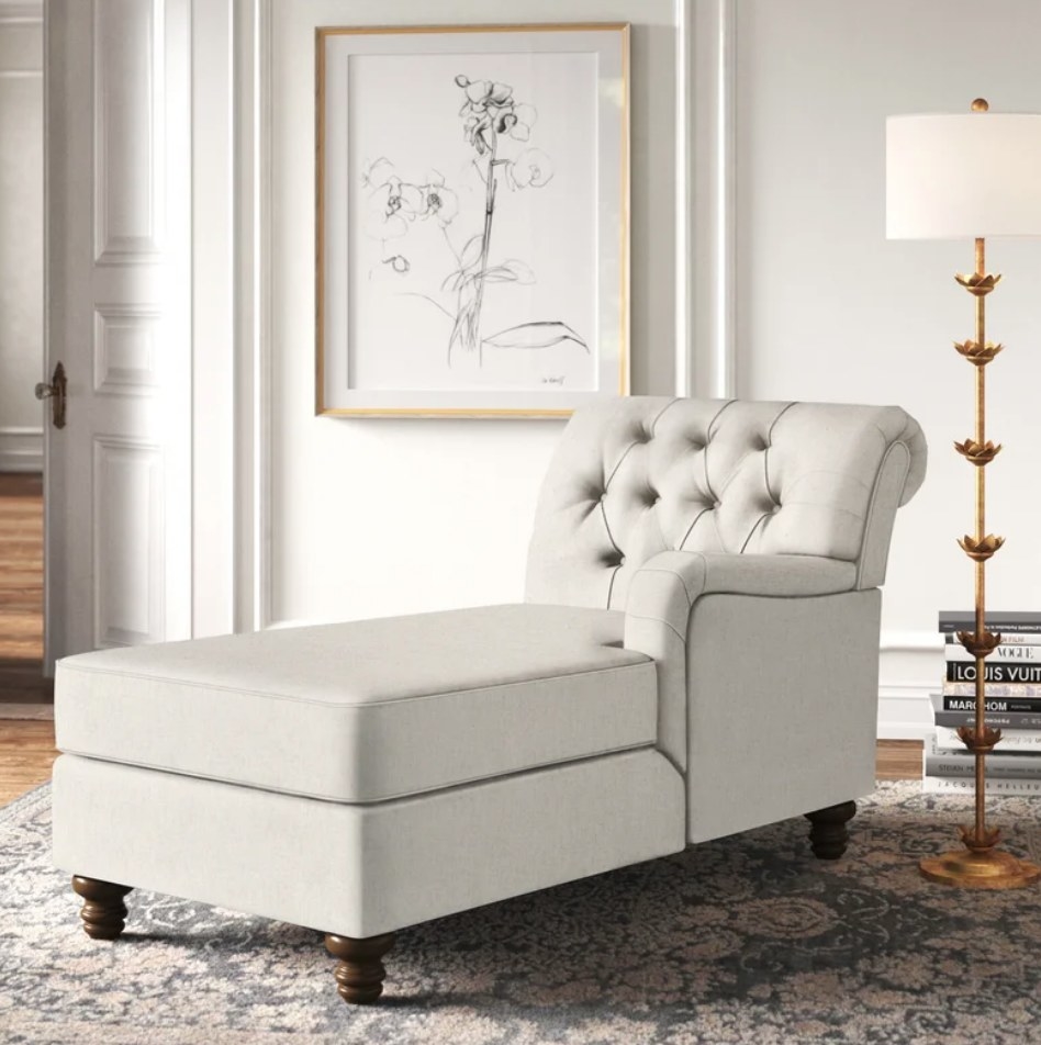 A white, chaise lounge with one arm displayed in a living room