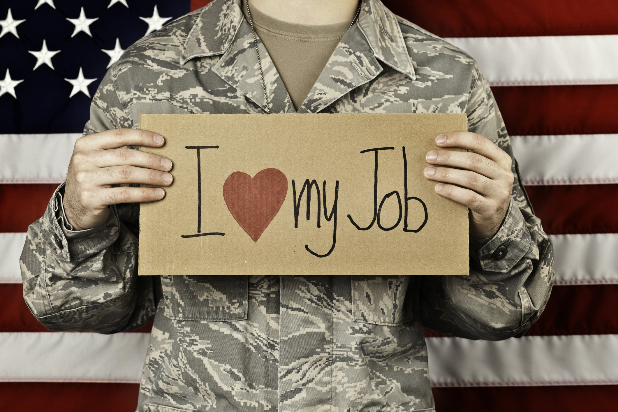 Soldier holding sign stating, &quot;I love my job.&quot;