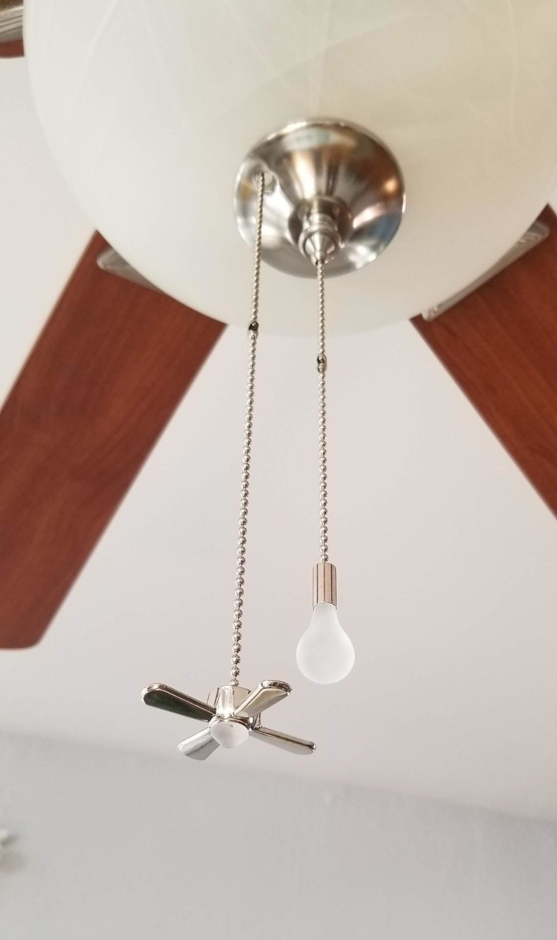 The product installed on a ceiling fan, one with a fan shaped pull and one with a lightbulb shape