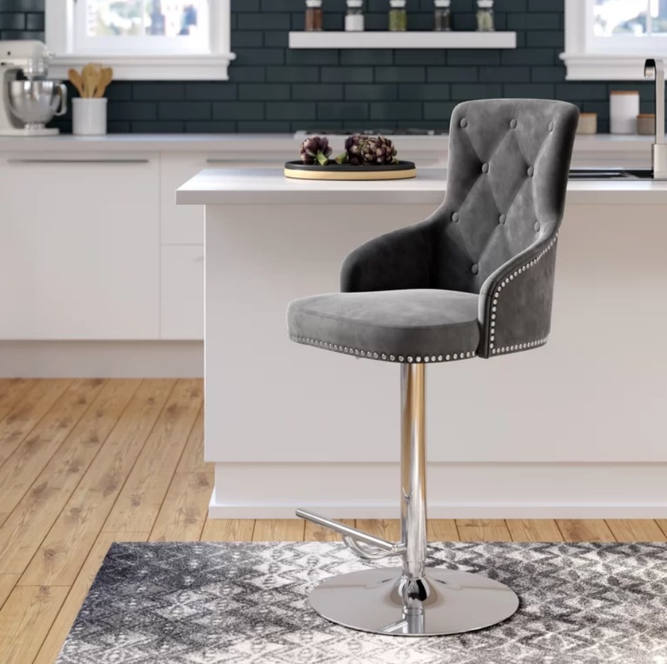 A grey, tufted bar stool with an adjustable swivel base