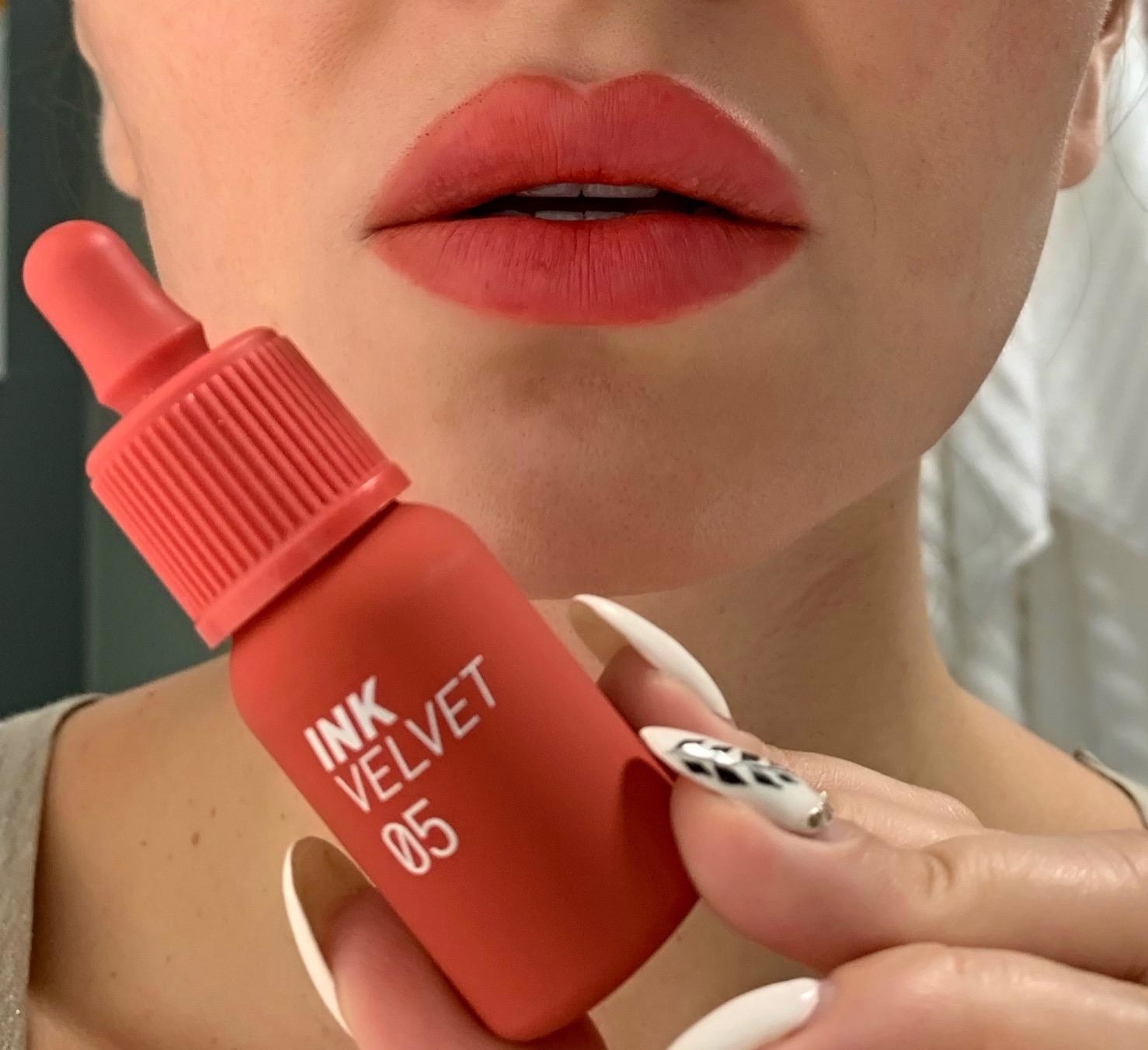 reviewer wearing the coral link ink and holding the product