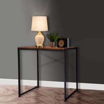 product image of the desk with lamp, plant, and clock on it
