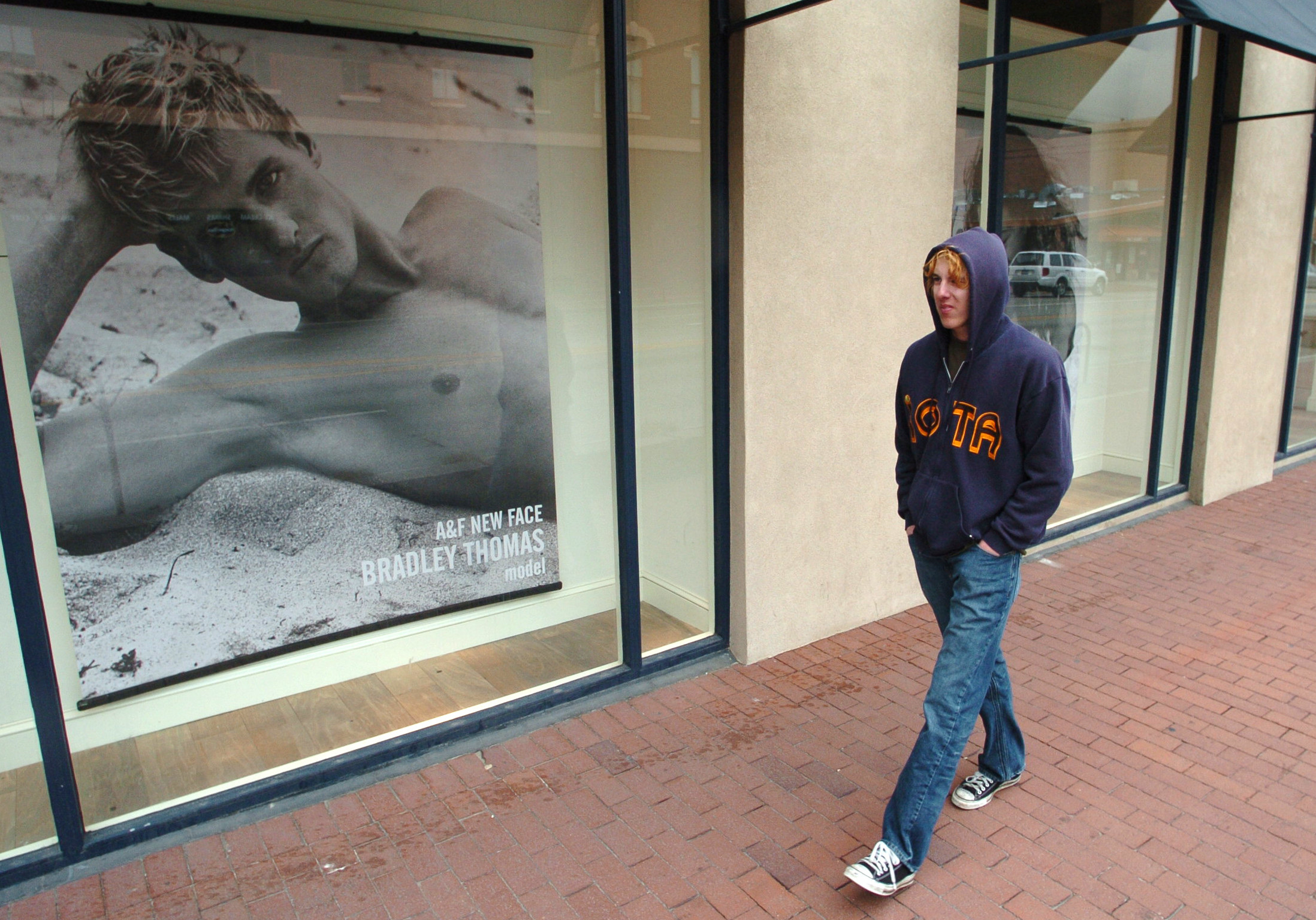Man walking by A&amp;amp;F store window with a photo of a shirtless man in it