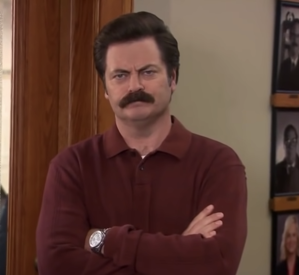 Ron Swanson from Parks and Rec with hands folded and frowning