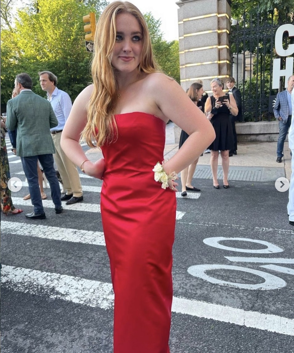 Rowan wears the strapless dress and a corsage on her wrist while posing near the event