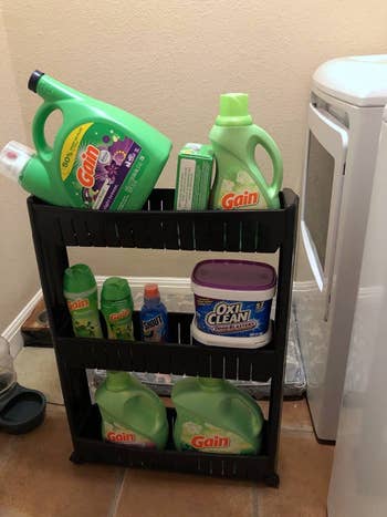 reviewer using the rolling storage tower with laundry essentials