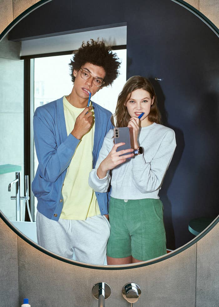 A selfie through a mirror of two people brushing their teeth.