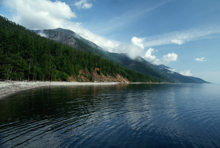 The shoreline and water of Lake Baikal with misty mountains in the distance