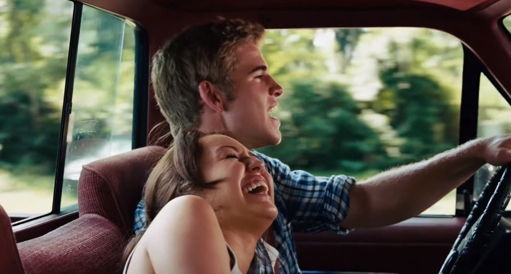 A young couple driving in a truck and laughing together