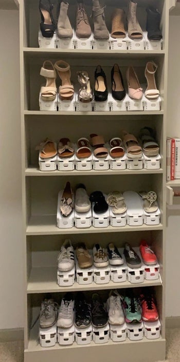 reviewer showing a shelving unit with lots of shoes on it that are stacked with white organizers