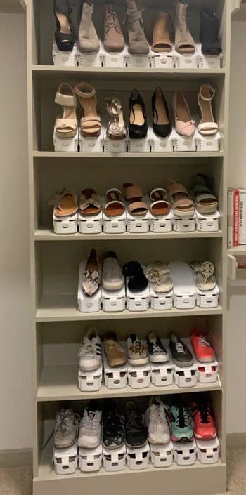reviewer photo of a shelving unit with lots of shoes on it that are stacked with white organizers