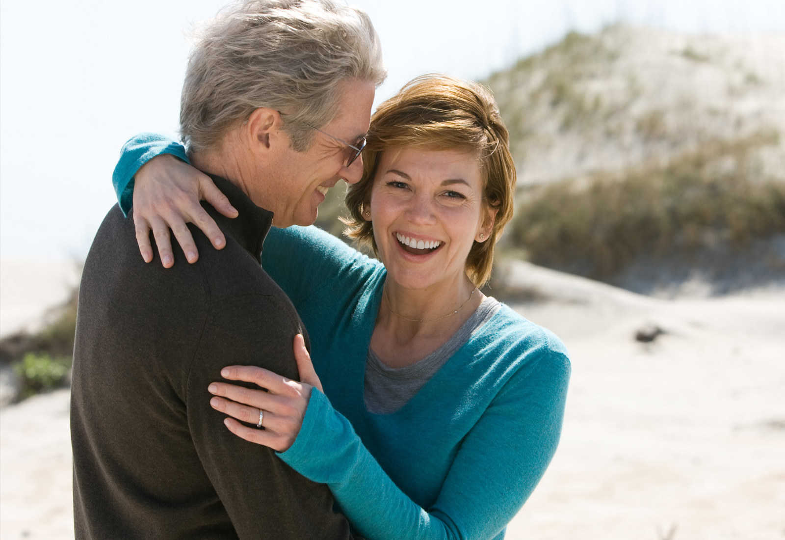 An older couple embracing on the beach while laughing