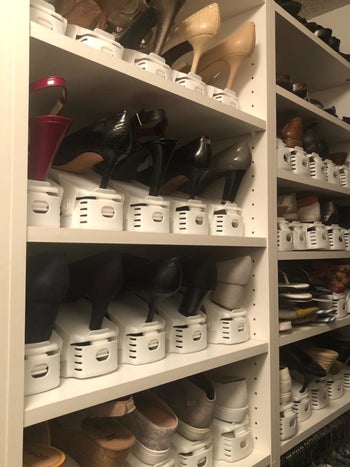 reviewer showing a shelving unit with lots of shoes on it that are stacked with white organizers