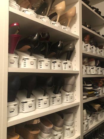 reviewer photo of a shelving unit with lots of shoes on it that are stacked with white organizers