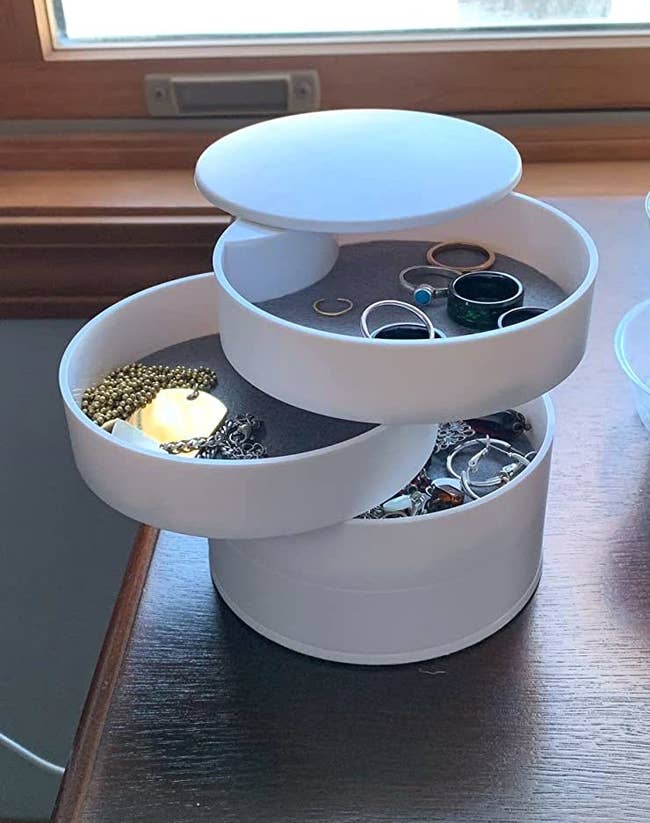 reviewer's cylindrical jewelry organizer opened up to reveal jewelry inside