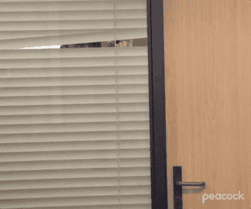 Michael peaks through the blinds of his office window