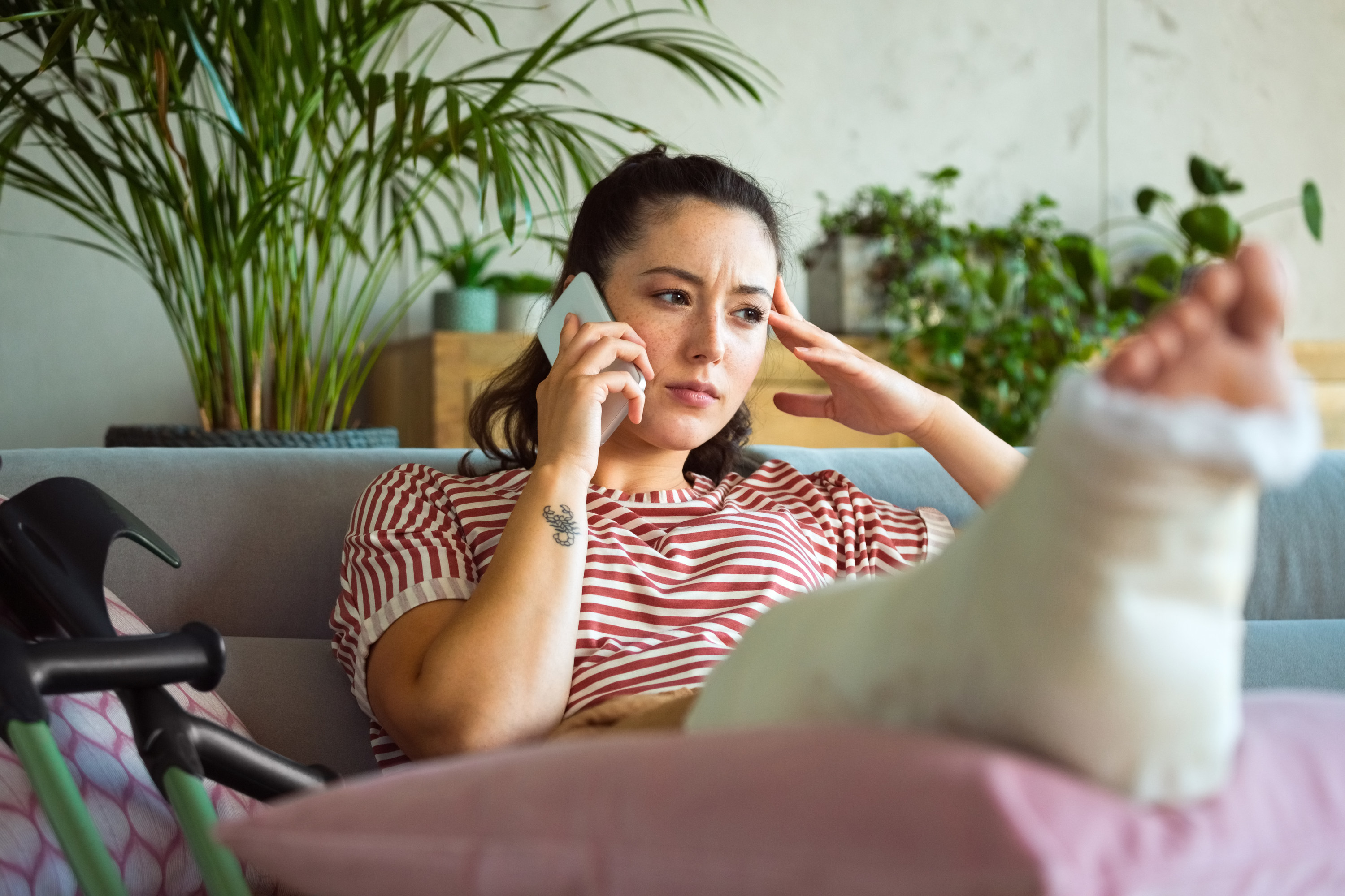 Woman with her leg in a cast on the phone at home