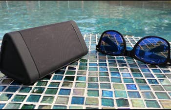 Reviewer's speaker sits on the ground next to the edge of a pool