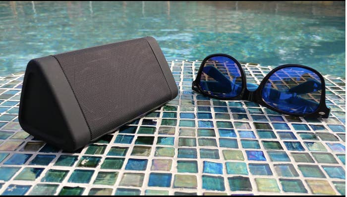 Reviewer&#x27;s speaker sits on the ground next to the edge of a pool