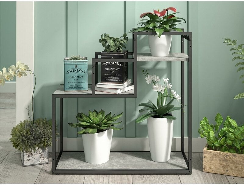 multi-level plant stand with marble colored shelves and metal frame