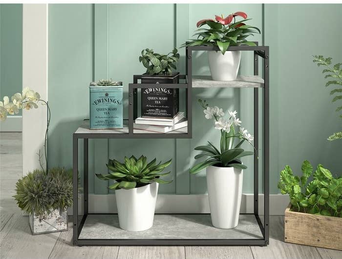 multi-level plant stand with marble colored shelves and metal frame