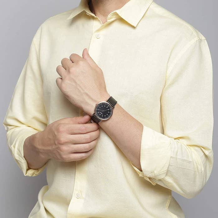 A man in a yellow shirt wearing a black and gold Timex watch