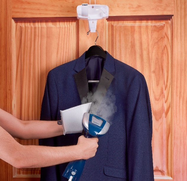 A model uses the steamer to press out wrinkles in professional blue suit jacket