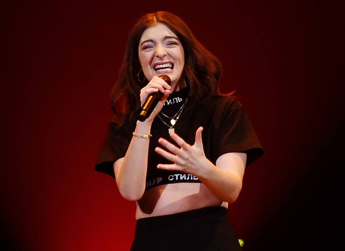 Lorde sings while wearing a black T-shirt crop top