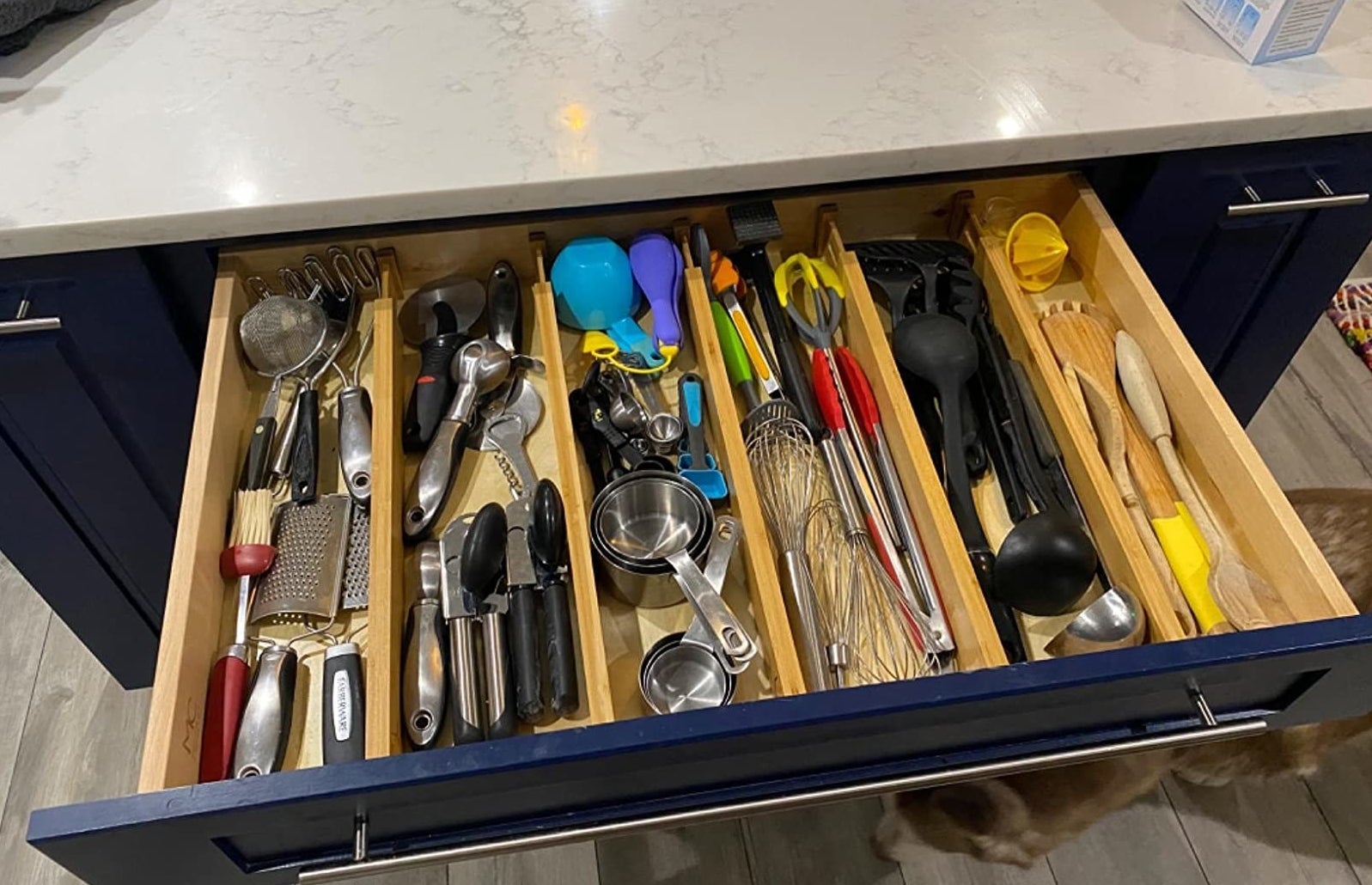 reviewer showing a big kitchen drawer with five bamboo drawer dividers organizing it