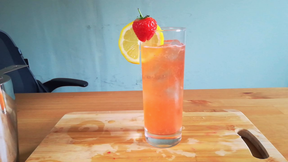 A strawberry lemonade mocktail in a highball glass.
