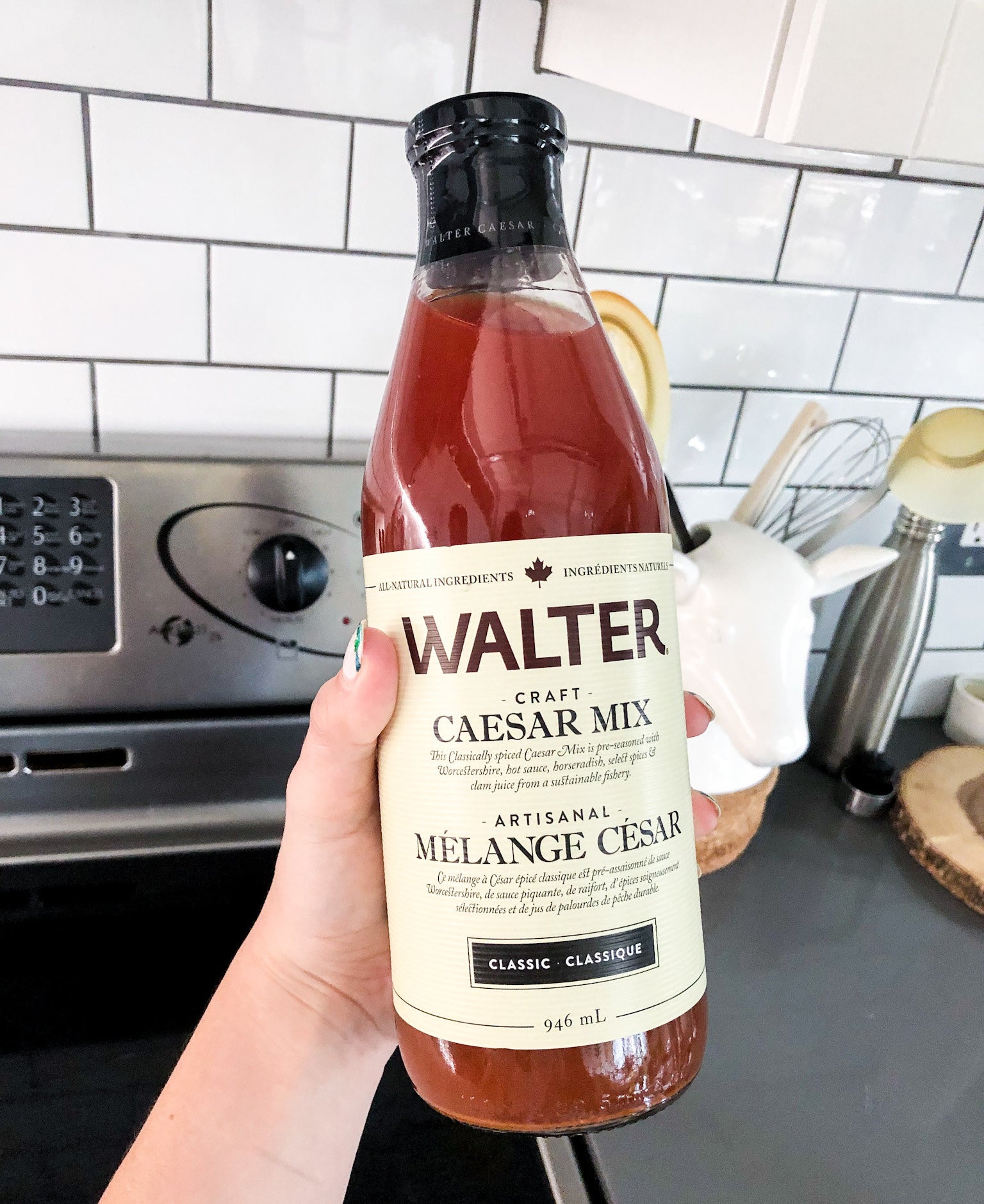 A person holding up a bottle of walter&#x27;s craft caesar mix
