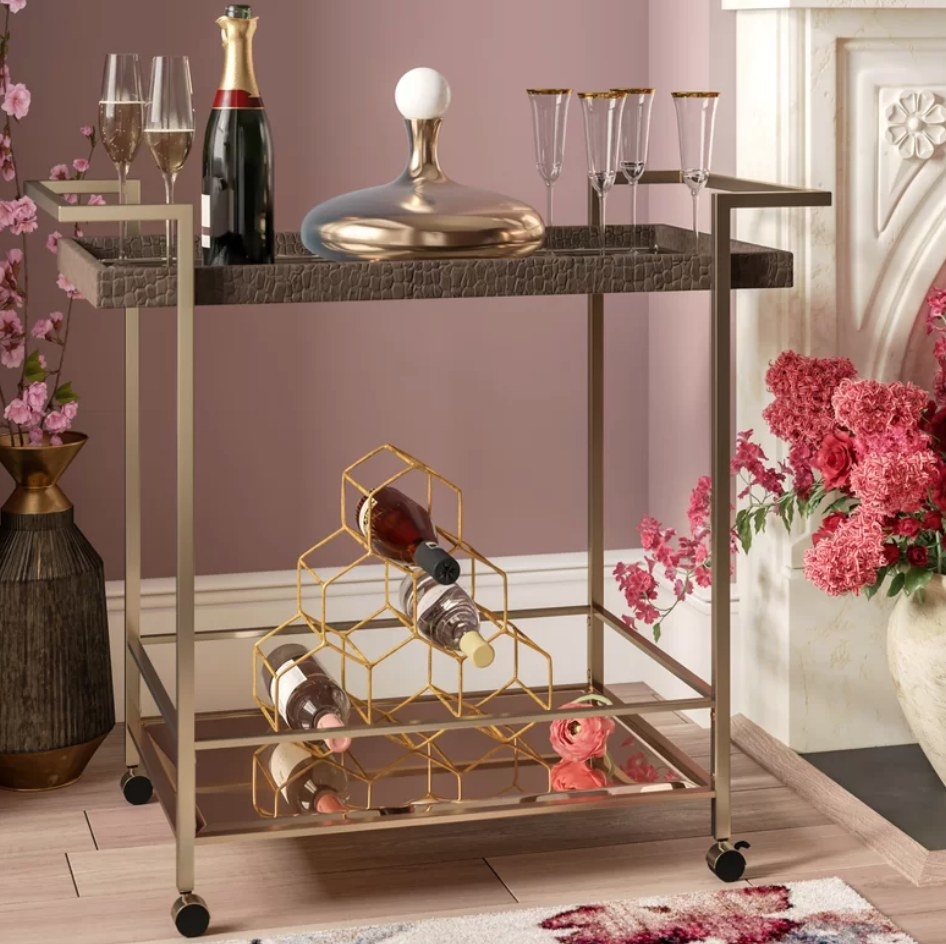 A mirror and metal bar cart filled with wine bottles and champagne glasses