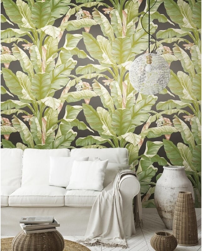 green and black banana leaf wallpaper behind a white couch