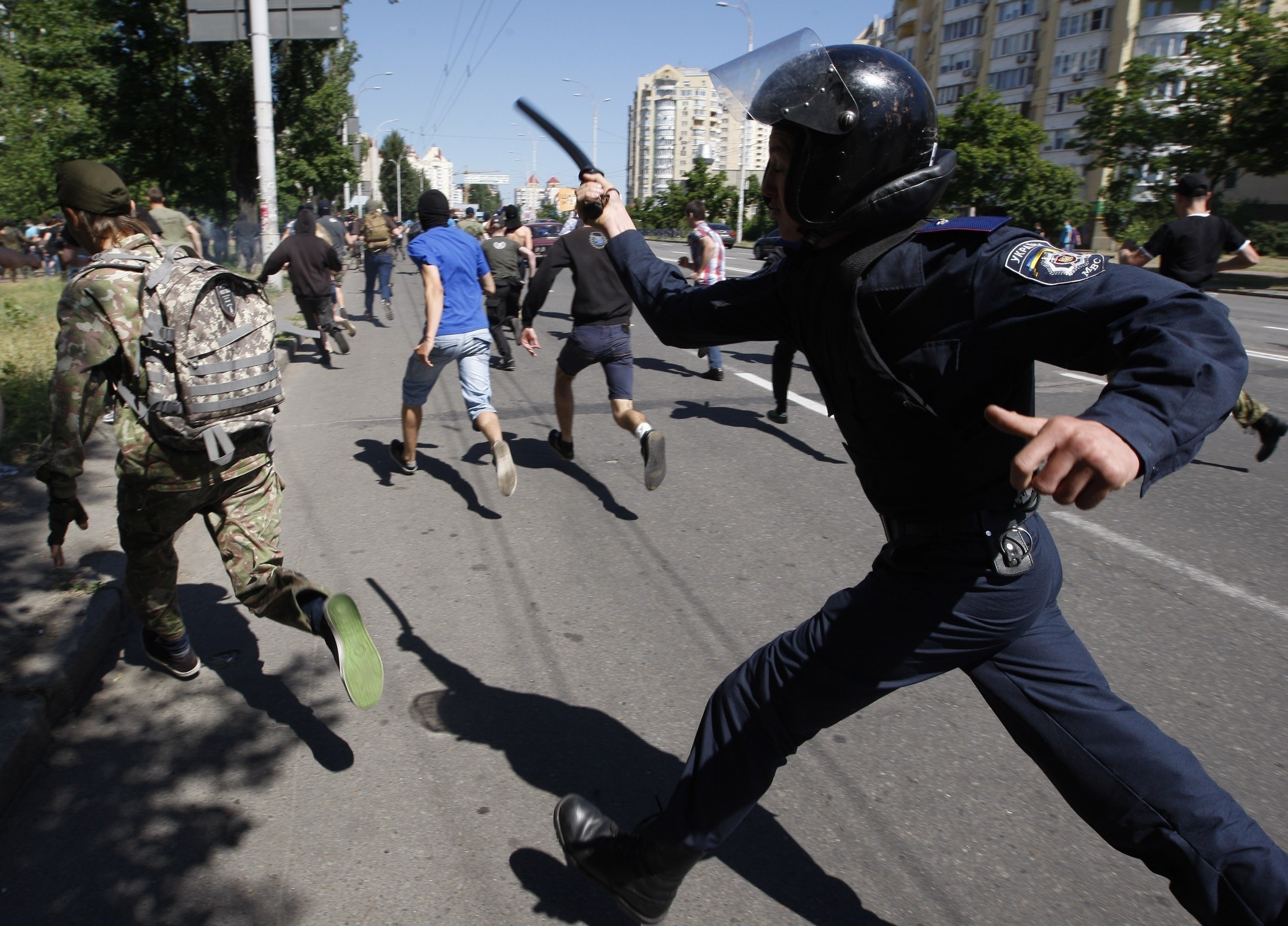 A police officer holding a baton runs after protesters