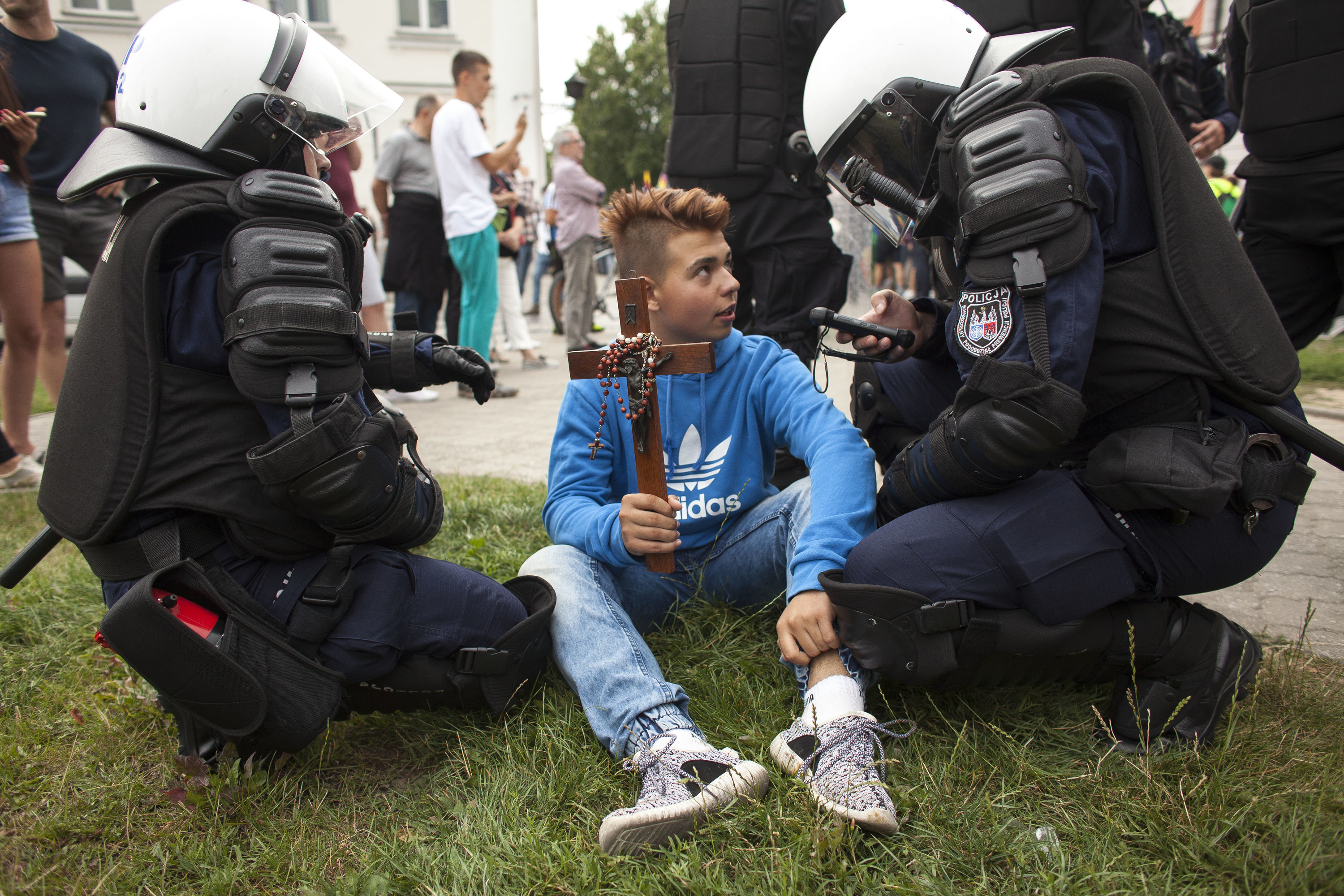 Officers kneel next to a kid holding a crucifix