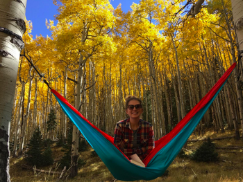 reviewer with hammock hung up on two quaking aspens, sitting cross legged in the center 