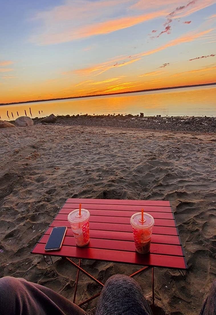 reviewer photo of a beach table in the sand with a sunset in the background