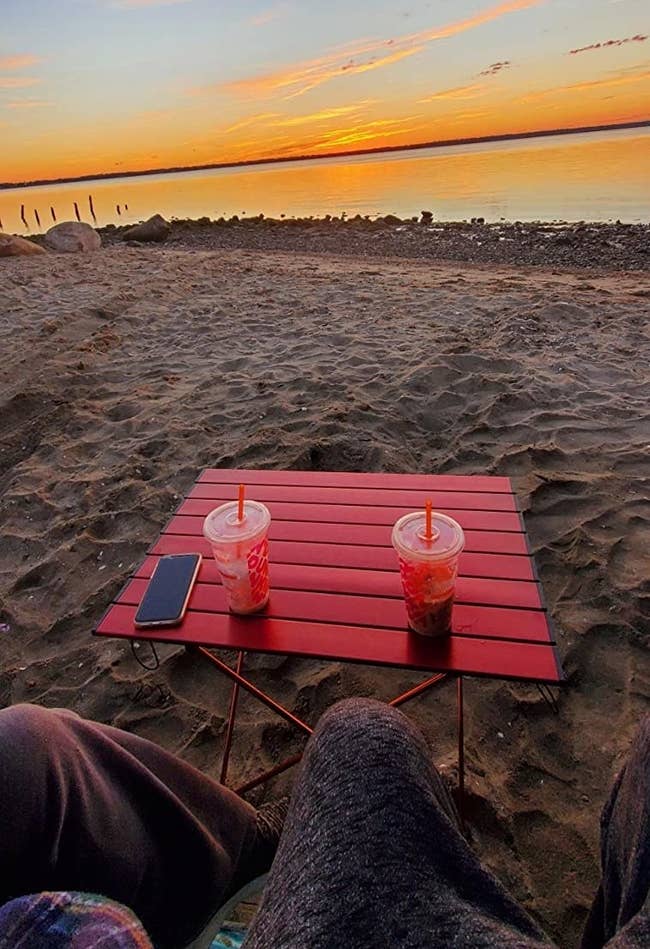 reviewer photo of a beach table in the sand with a sunset in the background