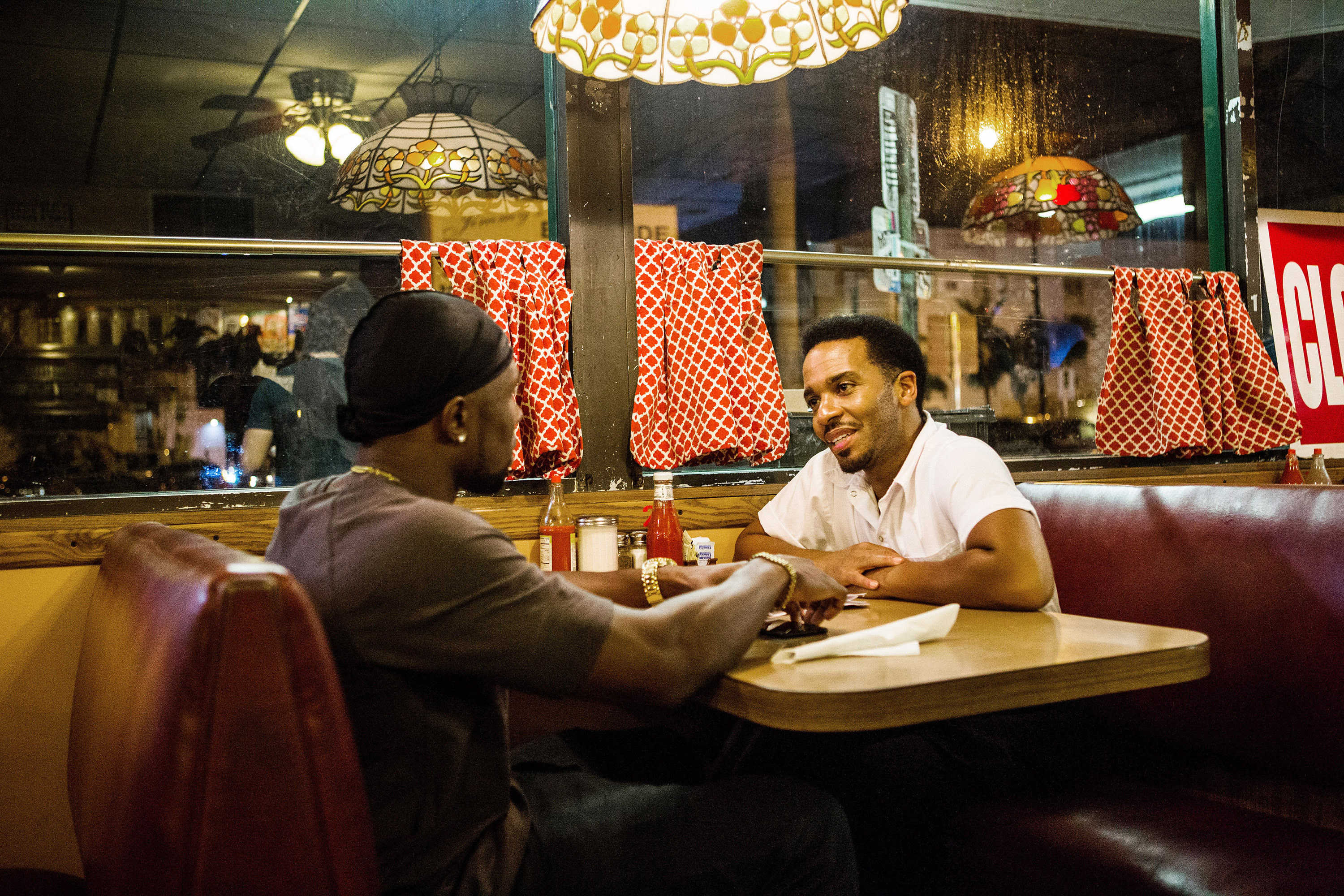 Trevante Rhodes sits across from Andre Holland in a diner