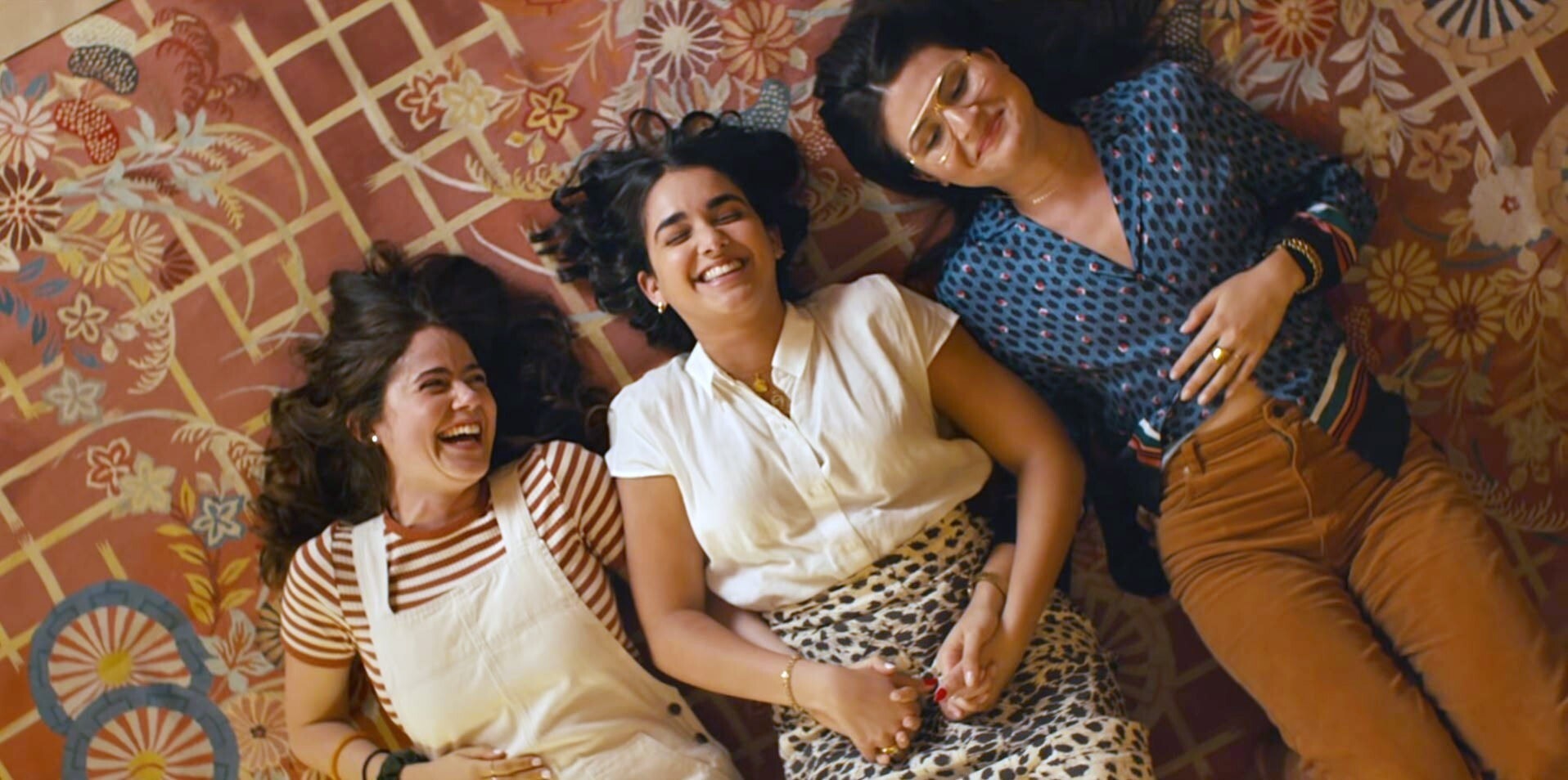 Molly Gordon, Geraldine Viswanathan, and Phillipa Soo laughing on the fllor