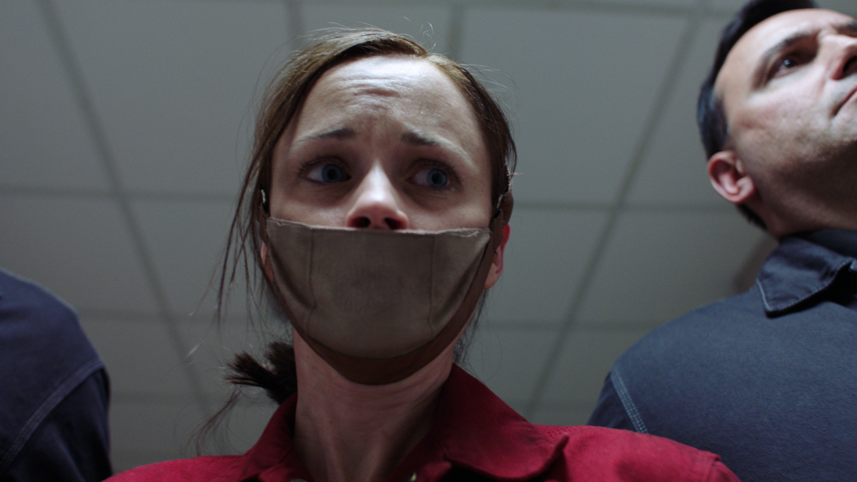 Alexis Bledel being led down a hallway by guards with a mask over her mouth