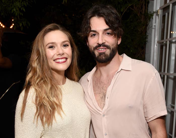 Elizabeth smiles while standing with Robbie at an event