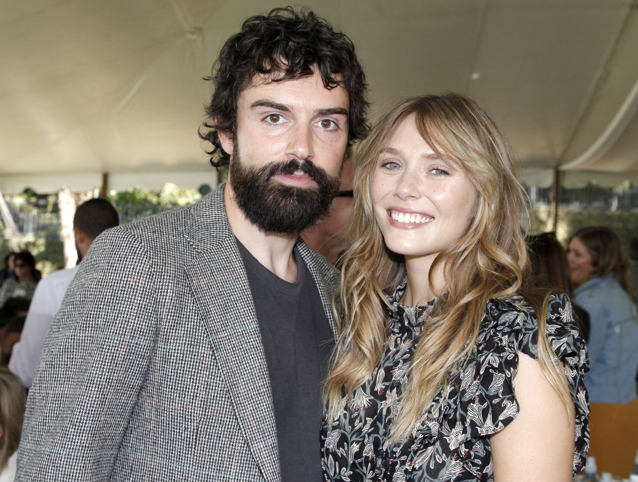 Elizabeth and Robbie stand close together at an outdoor event